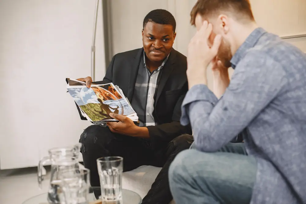 Image of a man in therapy, discussing his feelings with a counselor and undergoing a picture-based assessment.